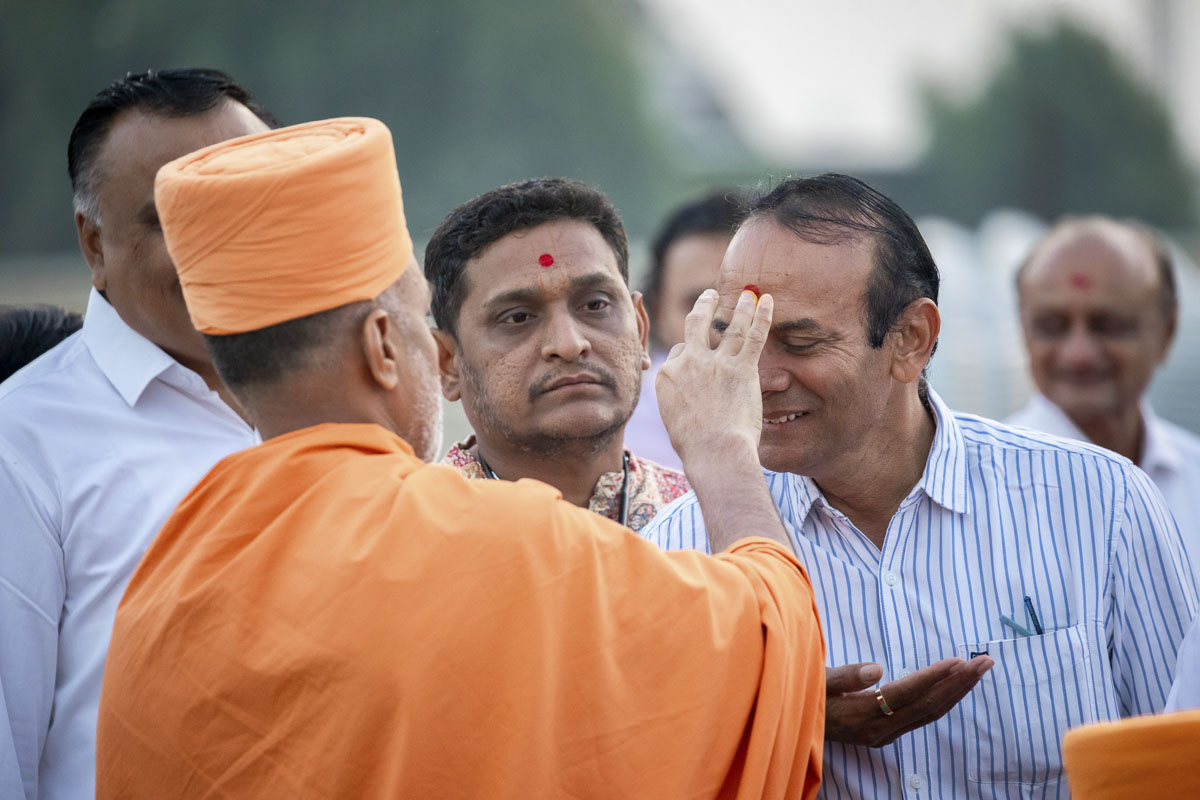 A sadhu applies chandlo to devotees