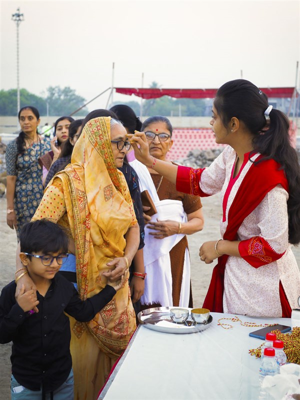 A karyakar applies chandlo to devotees