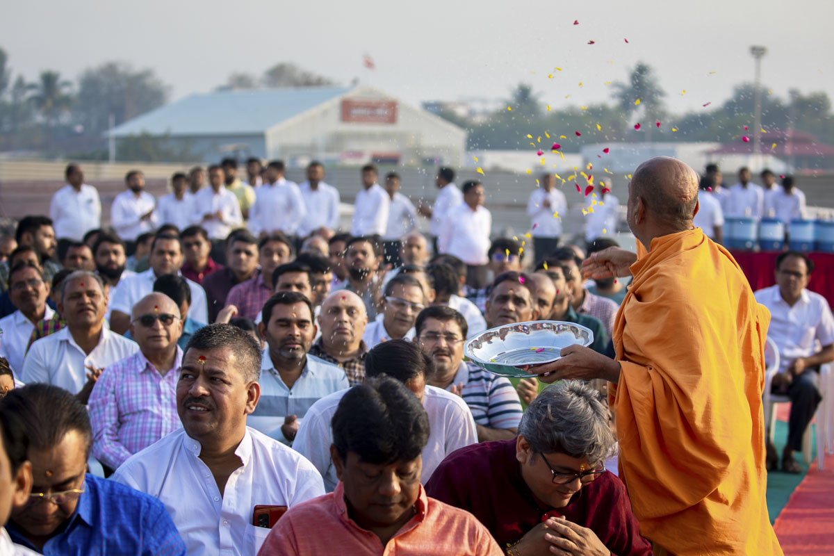 A sadhu showers flower petals on devotees