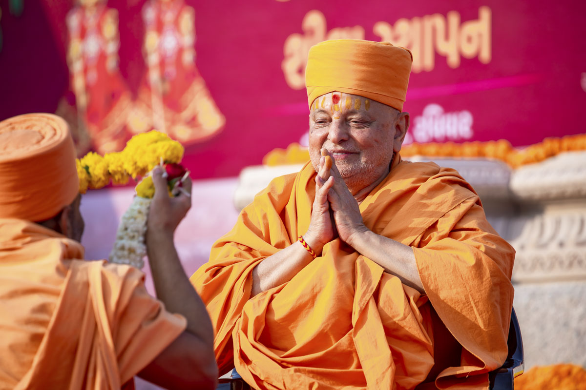 A sadhu honors Pujya Ishwarcharan Swami with a garland
