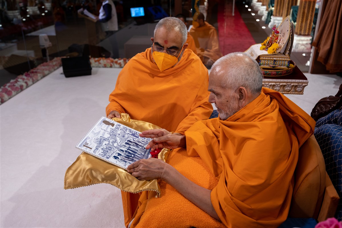 An enlarged copy of the Coronation stamp was ceremoniously presented to His Holiness Mahant Swami Maharaj
