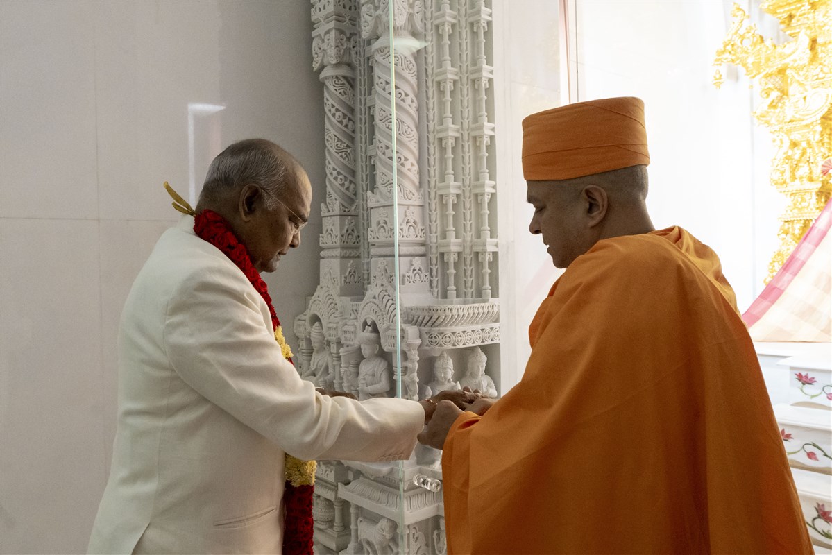 Swami Brahmaviharidas ties a nadachhadi on Shri Ram Nath Kovind’s wrist.