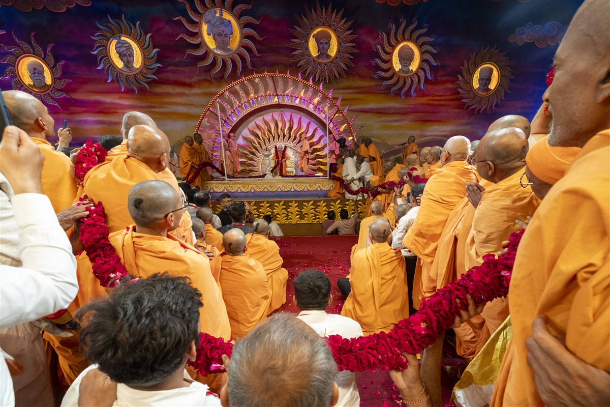 Swamis and karyakars honor Swamishri with a garland