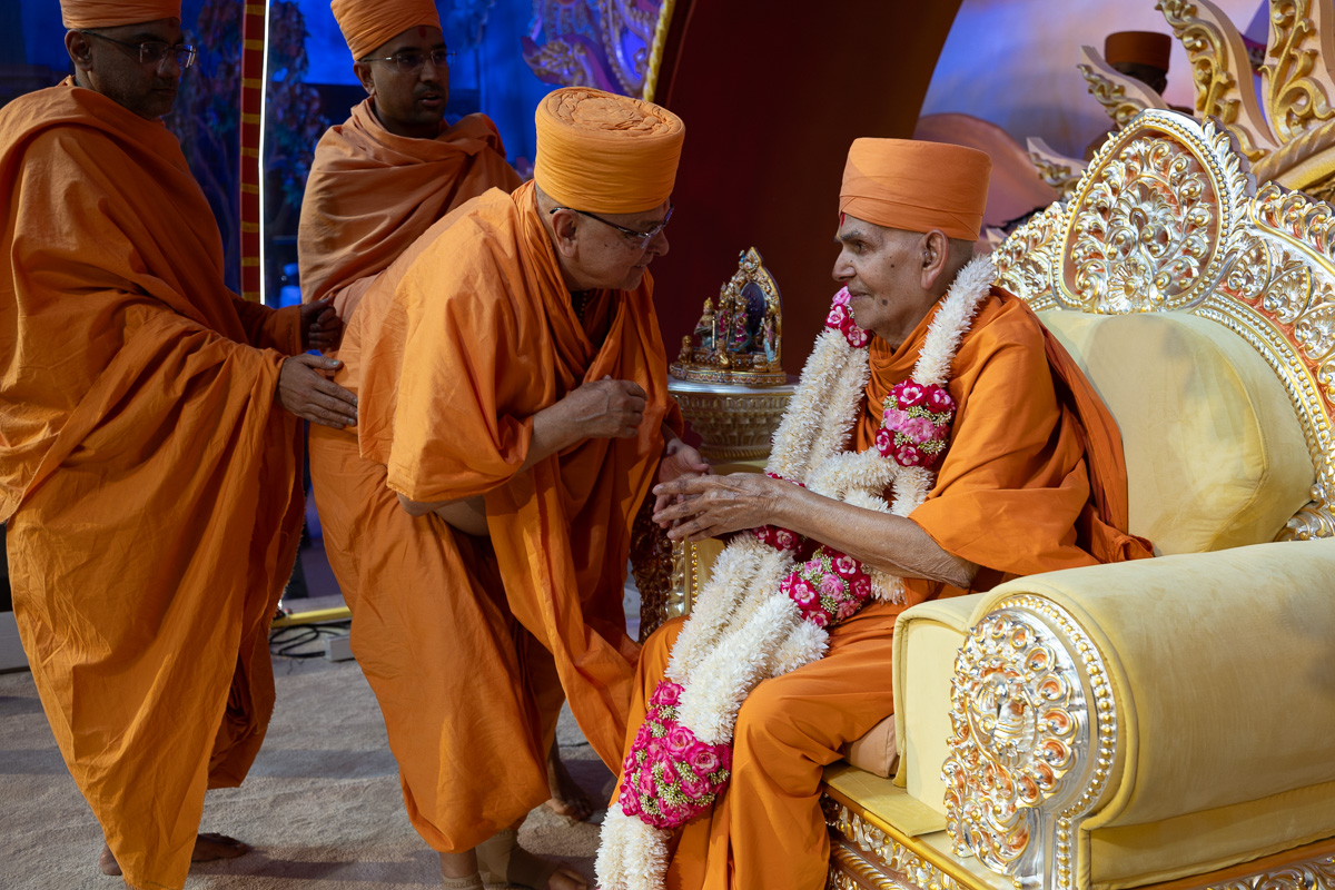 Pujya Ishwarcharan Swami honors Swamishri with a garland