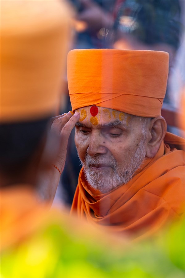 Pujya Ishwarcharan Swami applies chandan archa to Swamishri