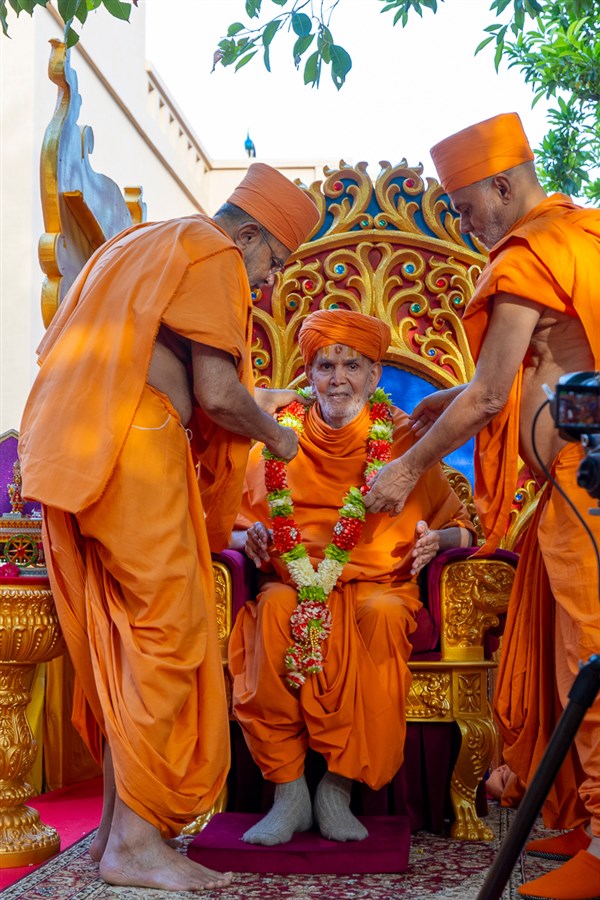 Pujya Viveksagar Swami and Gnaneshwar Swami honor Swamishri with a garland