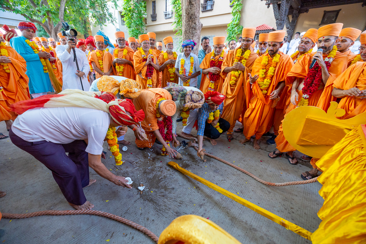 A swami and devotees split the coconut at the beginning of the Rathyatra